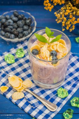 Böğürtlenli yoğurt, tahıl ve nane fışkın. Ahşap mavi arka plan. Üstten Görünüm. Yakın çekim