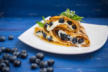 Krep yaban mersini, krem şanti ve nane limon balm bir delikanlı. Ahşap mavi arka plan. Yakın çekim.