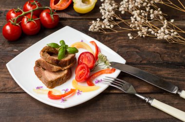 Domates, biber ve fesleğen ile pişmiş dilimlenmiş rulo köfte. Ahşap arka plan. Yakın çekim