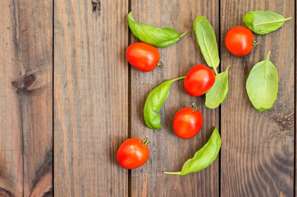 Pomodori con foglie di basilico su fondo di legno. Vista dall'alto — Foto Stock