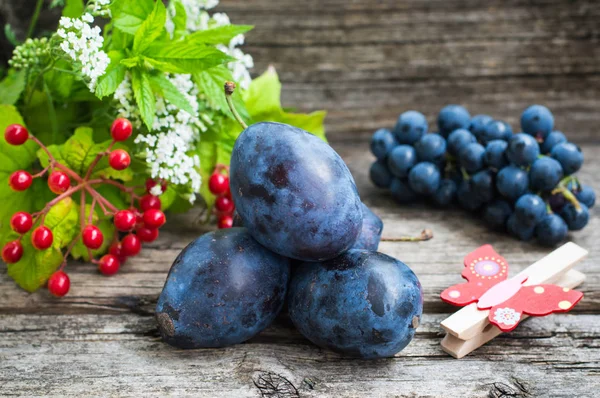 Plums dengan anggur pada latar belakang kayu. Pemandangan bagus. Close-up — Stok Foto