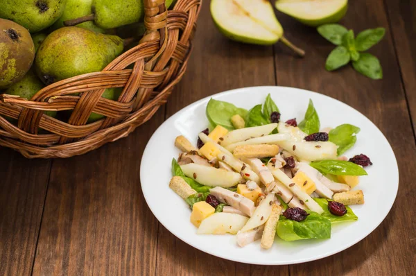 Chicken salad, pears, dried gooseberries and currants, cheese on basil leaves. Wooden background. Top view. Close-up — Stock Photo, Image