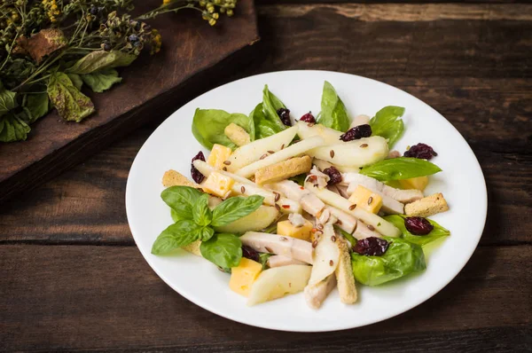 Salade de poulet, poires, groseilles et groseilles séchées, fromage sur feuilles de basilic. Fond en bois. Vue de dessus. Gros plan — Photo