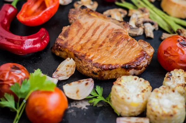 Stek med ben med grönsaker kokta grillen. Svart sten bakgrund. Ovanifrån. Selektivt fokus närbild — Stockfoto