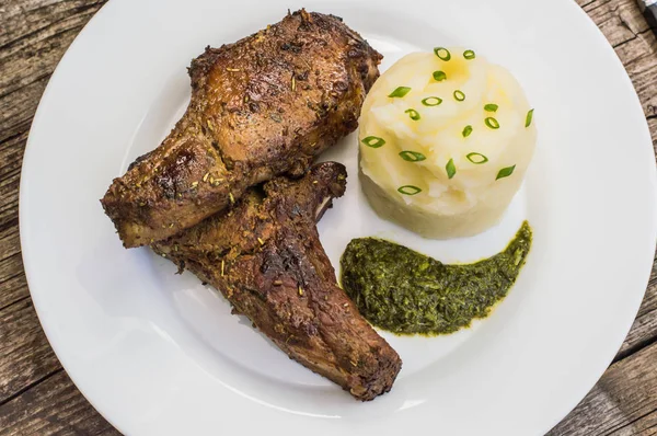 Bistecca di maiale all'osso alla griglia con purè di patate e salsa di erbe spinaci. Sfondo in legno. Primo piano. Vista dall'alto — Foto Stock