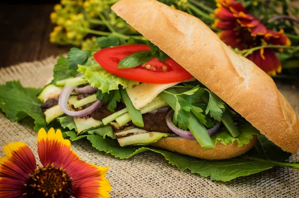 Sandwich avec steak de veau, légumes verts, courgettes, tomates, fromage et sauce moutarde. Fond en bois. Gros plan. Concentration sélective — Photo