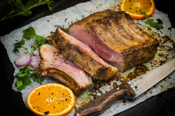 Bagt svinekød ribben med sauce og basilikum på et sort bord. Øverste udsigt. Nærbillede. Selektivt fokus - Stock-foto