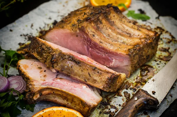 Gebackene Schweinerippchen mit Sauce und Basilikum auf einem schwarzen Tisch. Ansicht von oben. Nahaufnahme. Selektiver Fokus — Stockfoto