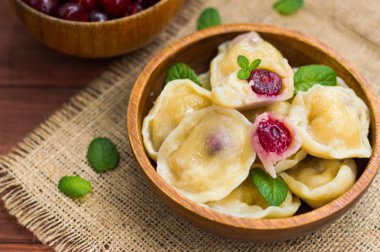 Köfte bir kiraz ve nane ile arka planını çiçekler çuval bezi üzerinde bırakır. Ahşap masa. Üstten Görünüm. Yakın çekim