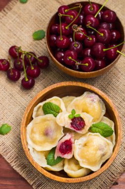 Köfte bir kiraz ve nane ile arka planını çiçekler çuval bezi üzerinde bırakır. Ahşap masa. Üstten Görünüm. Yakın çekim