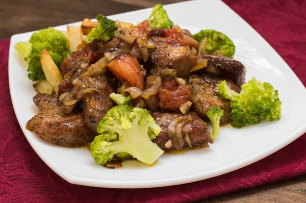 Stifado - un plat traditionnel chypriote, répandu en Grèce. Il se compose de ragoût avec des tomates, des pommes de terre, du brocoli, des oignons, de l'ail et des épices épicées. Table rustique en bois. Vue de dessus. Gros plan — Photo