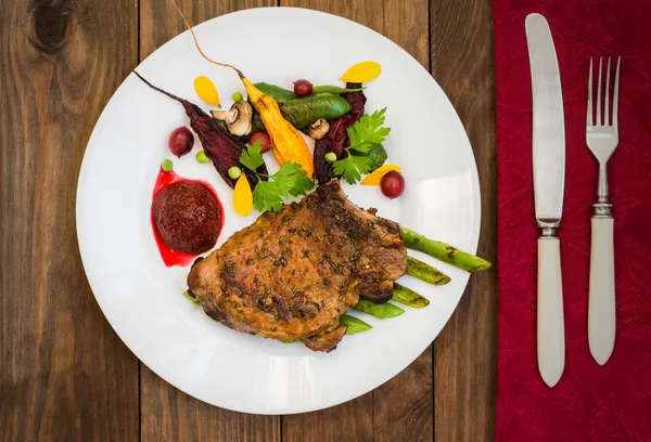 Stekt grillad Fläskstek med ben med grönsaker, mosade rödbetor och bärsås. Trä bakgrund. Ovanifrån. Närbild — Stockfoto