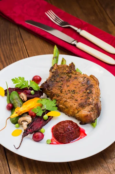 Fried Grilled pork steak on the bone with vegetables, mashed beetroot and berry sauce. Wooden background. Top view. Close-up — Stock Photo, Image