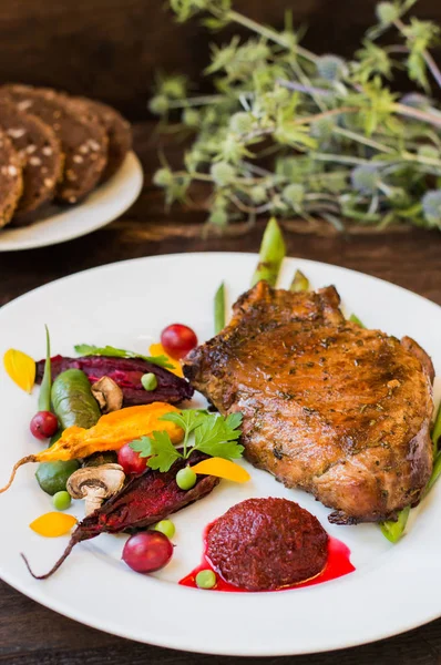 Stekt grillad Fläskstek med ben med grönsaker, mosade rödbetor och bärsås. Trä bakgrund. Ovanifrån. Närbild — Stockfoto