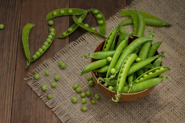 Ärtskidor i en träskål på säckväv. bakgrund. Ovanifrån. Närbild — Stockfoto