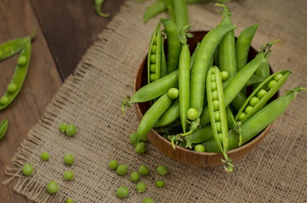 Ärtskidor i en träskål på säckväv. bakgrund. Ovanifrån. Närbild — Stockfoto