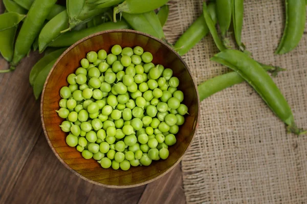 Ärtskidor i en träskål på säckväv. bakgrund. Ovanifrån. Närbild — Stockfoto