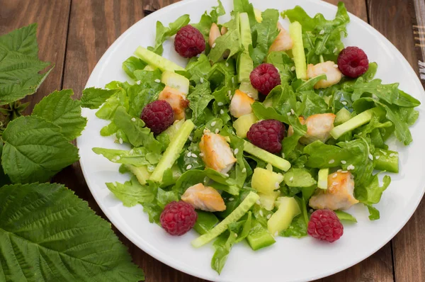 Salad dengan raspberry, arugula, mentimun, paprika, ayam panggang dan wijen. Latar belakang kayu. Close-up — Stok Foto