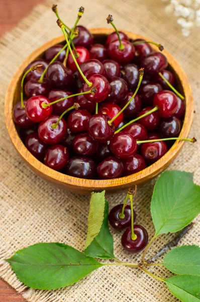 Cerises fraîches dans un bol sur la table. Fond en bois. Gros plan — Photo