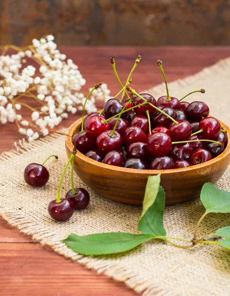 Cerises fraîches dans un bol sur la table. Fond en bois. Gros plan — Photo