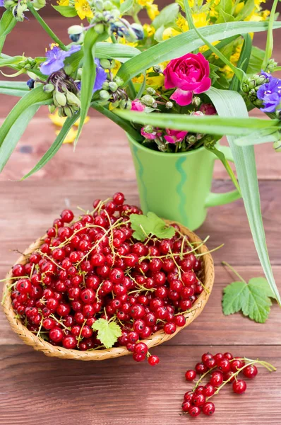 Groseilles rouges sur un fond de fleurs. Table en bois. Gros plan — Photo