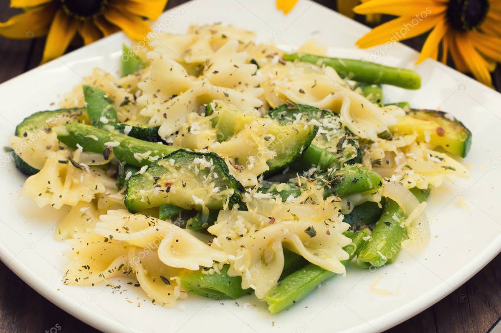Pasta Primavera - its delicious, hearty and healthy dishes from South Italy. Wooden rustic background with flowers. Top view. Close-up.