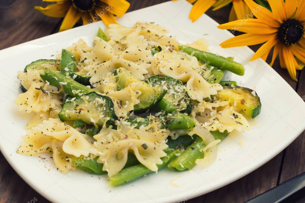 Pasta Primavera - its delicious, hearty and healthy dishes from South Italy. Wooden rustic background with flowers. Top view. Close-up.