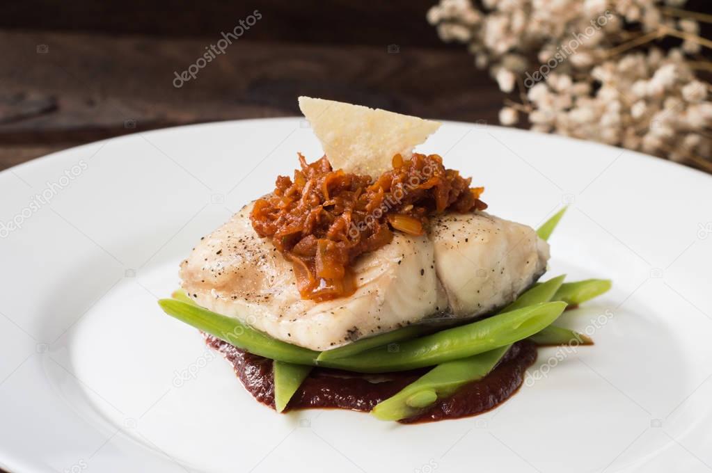 Cooked fish with steamed asparagus, vegetable ragout, tomato sauce and potato chips. Wooden background. Top view. Close-up