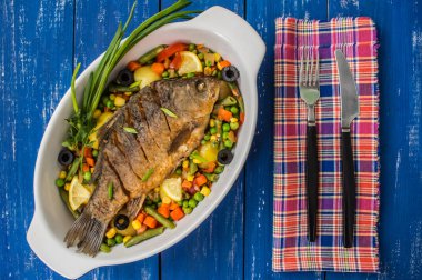 Otlar ve limon eski ahşap arka plan, üstten görünüm ile kahverengi plaka üzerinde ızgara balık. Akdeniz lüks deniz ürünleri kavramı.