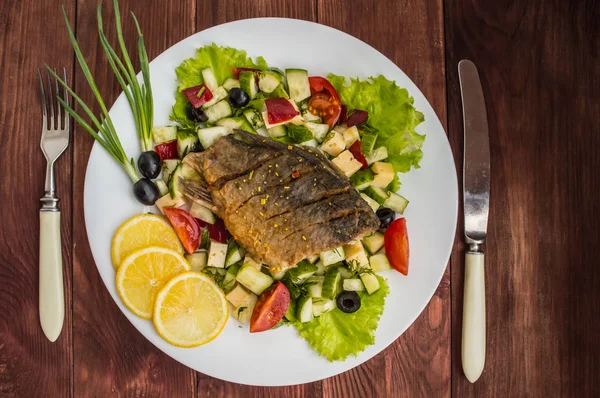 Filé de peixe frito em uma cama de salada Caesar. Fundo de madeira. Vista superior . — Fotografia de Stock