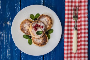 Kuş üzümü ile Cheesecakes mavi ahşap zemin üzerine pudra şekeri kaplı. Üstten Görünüm