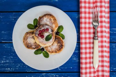 Kuş üzümü ile Cheesecakes mavi ahşap zemin üzerine pudra şekeri kaplı. Üstten Görünüm