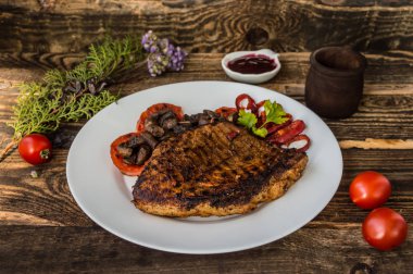 Mantar, domates ve biber beyaz bir plaka üzerinde ızgara biftek. Ahşap arka plan