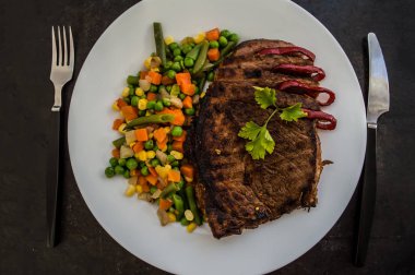 Beyaz tabakta haşlanmış sebzeli ızgara biftek. eski tablo. Üstten Görünüm
