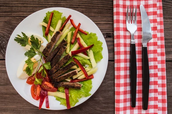 Salada de carne assada, alface, ovos cozidos, páprica, tomate e pepino em uma mesa de madeira. Vista superior — Fotografia de Stock