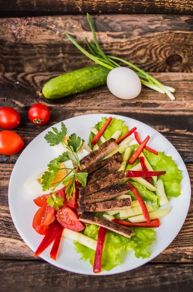 Saláta, sült hús, saláta, főtt tojás, paprika, paradicsom és uborka, egy fából készült asztal. Szemközti nézet — Stock Fotó