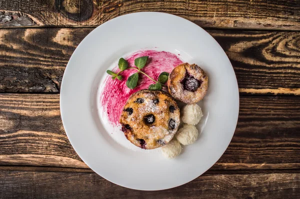 Cheesecakes with cherries and currants covered  powdered sugar on a wooden background. Top view — Stock Photo, Image