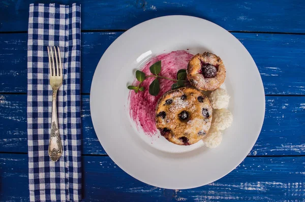 Cheesecakes with cherries and currants covered  powdered sugar on a blue wooden background. Top view — Stock Photo, Image