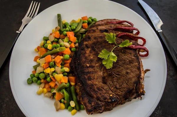Steak vom Grill mit gedünstetem Gemüse auf einem weißen Teller. alter Tisch. Ansicht von oben — Stockfoto