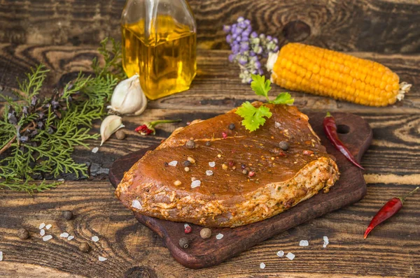 Gemarineerde biefstuk met kruiden op een houten tafel — Stockfoto