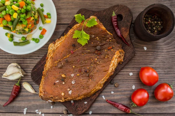 Gemarineerde biefstuk met kruiden op een houten tafel — Stockfoto