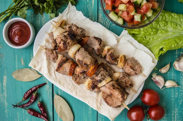 Schweinefleisch mit Gemüse am Spieß auf einem türkisfarbenen Tisch gekocht. hölzerner Hintergrund — Stockfoto