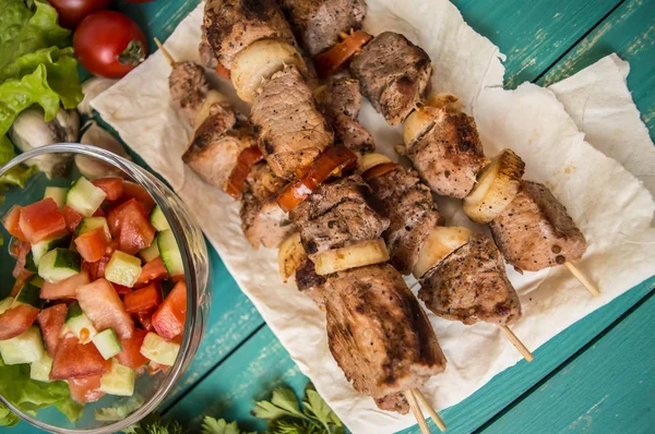 Schweinefleisch mit Gemüse am Spieß auf einem türkisfarbenen Tisch gekocht. hölzerner Hintergrund — Stockfoto