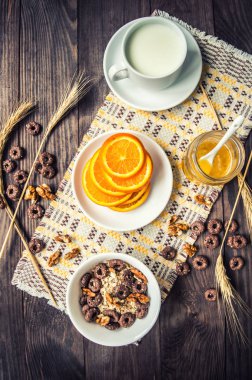 Mısır gevreği, taze süt ve portakal dilimleri kahvaltı. Ahşap bir arka plan üzerinde. Üstten Görünüm. Yakın çekim