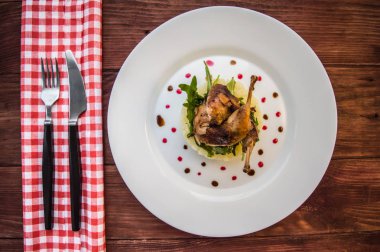 Kavrulmuş bıldırcın bir yatakta patates püresi, roket yaprakları ve berry sos ile. Beyaz tabak ahşap rustik arka plan. Üstten Görünüm. Yakın çekim