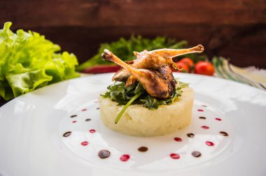 Kavrulmuş bıldırcın bir yatakta patates püresi, roket yaprakları ve berry sos ile. Beyaz tabak ahşap rustik arka plan. Üstten Görünüm. Yakın çekim