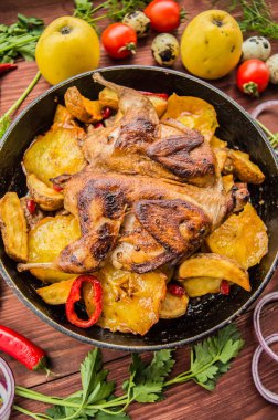 Bıldırcın patates ve elma ile bir tavada pişirdim. Kahverengi ahşap zemin üzerinde. Üstten Görünüm. Yakın çekim