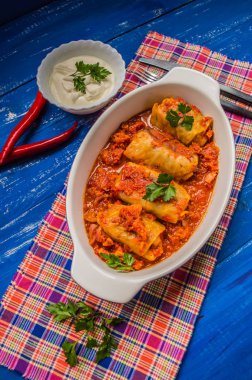 Akşam yemeği domates soslu lahana rulo ile dekore edilmiş maydanoz. Ahşap rustik arka plan mavi. Üstten Görünüm. Yakın çekim