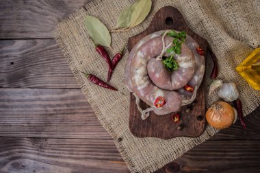 Koyu ahşap arka plan üzerinde baharatlar ile çiğ sosis. Üstten Görünüm. Yakın çekim