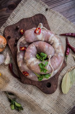 Koyu ahşap arka plan üzerinde baharatlar ile çiğ sosis. Üstten Görünüm. Yakın çekim